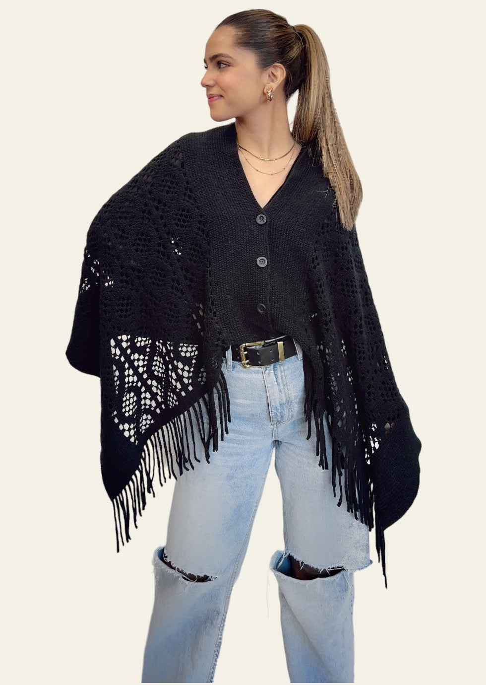 Black Knitted Cardishawl. The soft, textured knit creates a cozy and breathable feel, while the loose, open design adds effortless charm and movement. Frontal view. The piece falls gracefully, offering a stylish, laid-back look that remains both comfortable and chic.