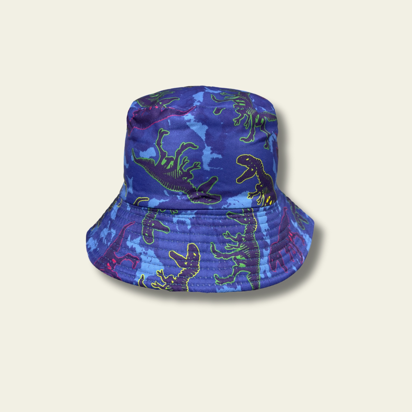 This reversible bucket hat is designed for children, offering protection from the sun with a functional and simple design. One side of the hat features a dinosaur print in shades of blue and green, while the reverse side is a solid green color. Made from lightweight fabric, the hat is breathable and provides a comfortable fit for outdoor activities.
